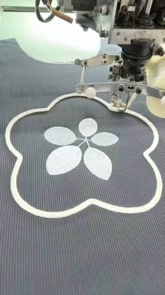 Embroidery machine stitching a floral outline on ribbed fabric